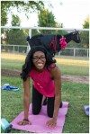 black goat on girls back kneeling on a pink yoga mat